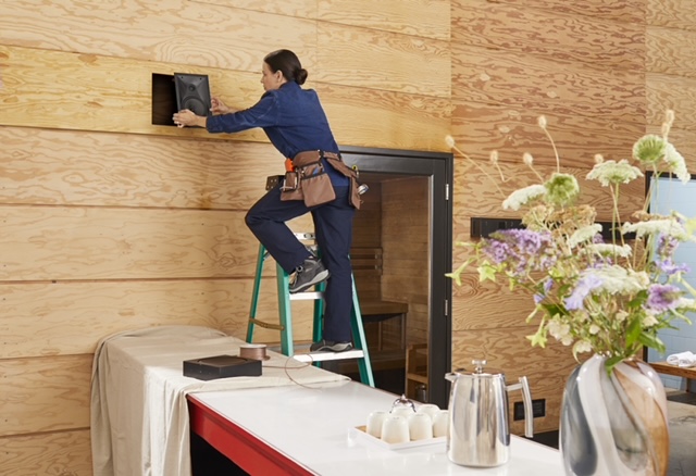 A technician on a ladder installing an audio and video system